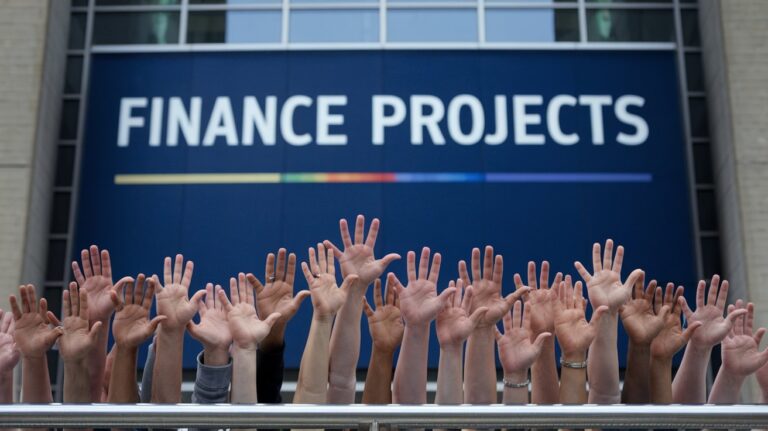 a group of hands raised in front of a blue sign